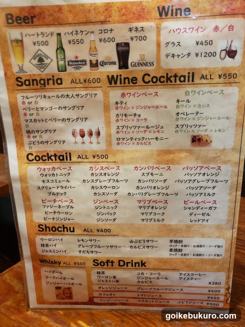 A printed menu board displaying various alcoholic beverages including Beer, Wine, Sangria, Wine Cocktail, Cocktail, Shochu, Whisky, and Soft Drink with prices in yen.