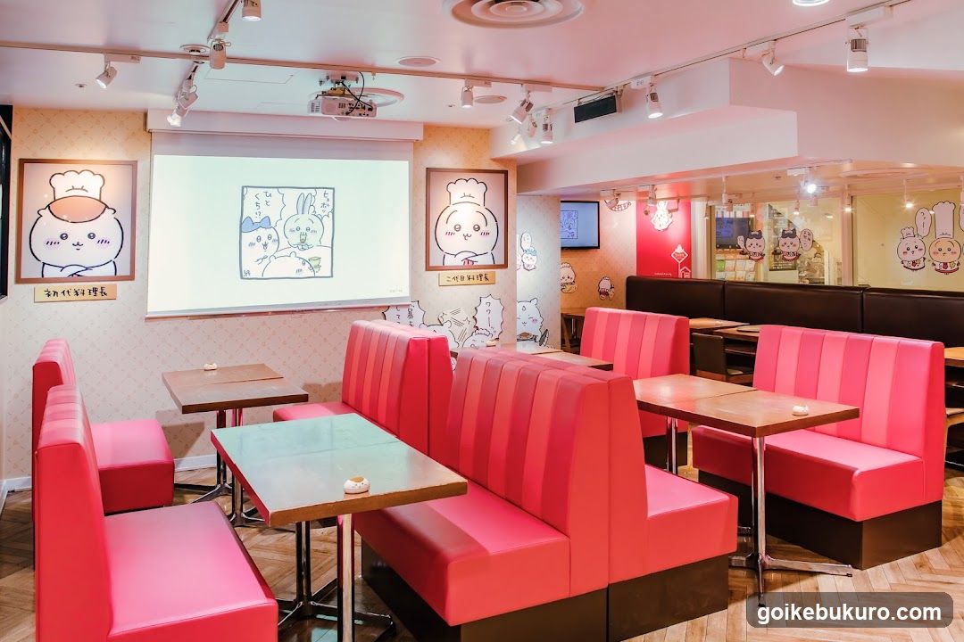 Interior of a Japanese-style restaurant or cafe with pink booth seating and wall art featuring cartoon characters.