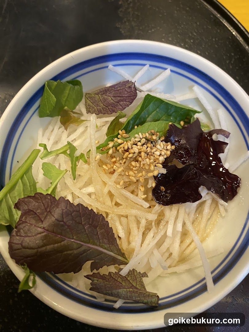Bowl of shredded vegetables with greens and sesame seeds