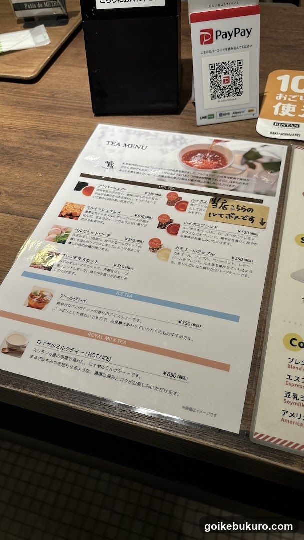 A printed tea menu displayed on a wooden table, featuring various hot and cold teas with prices in yen.
