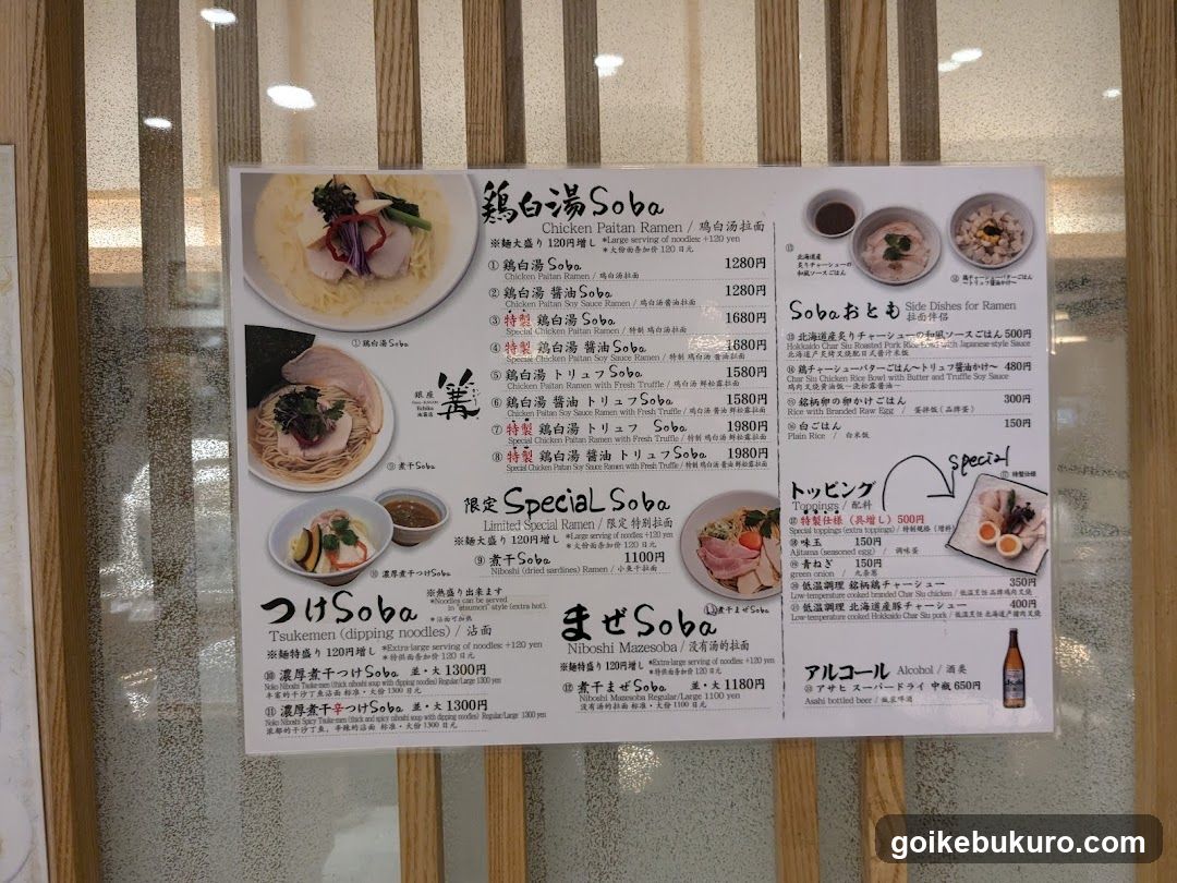 A printed menu board mounted on a glass window, featuring Japanese dishes like Chicken Futan Ramen, Tofu Soba, and Tsukemen.