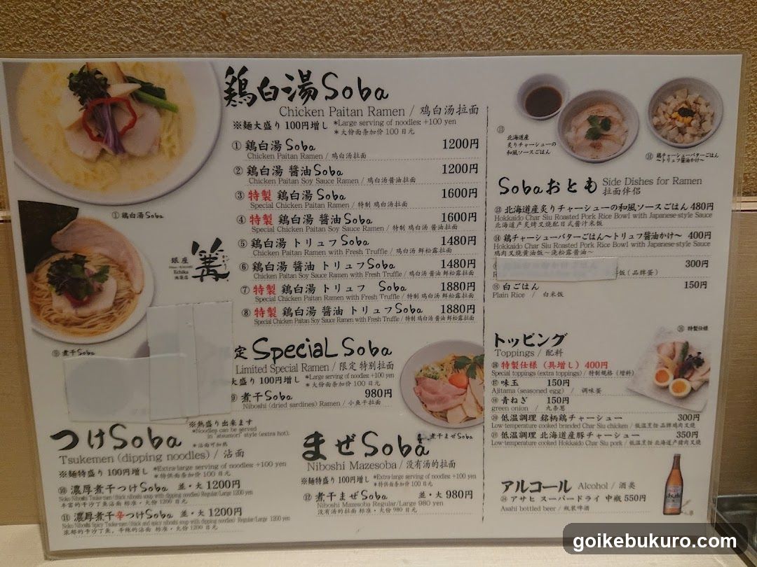 A printed menu board featuring Japanese and English text, listing various ramen and soba dishes with prices in yen.