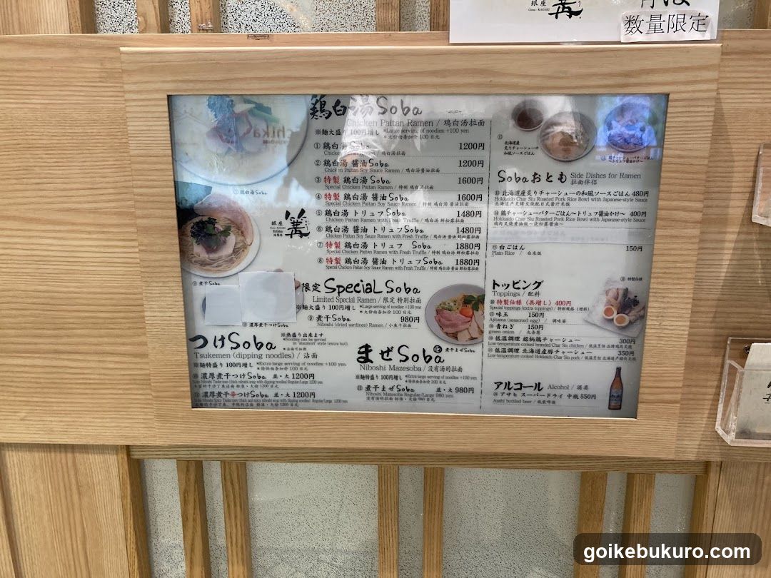 A framed menu board displaying various soba noodle dishes with prices in yen, including regular and special varieties.