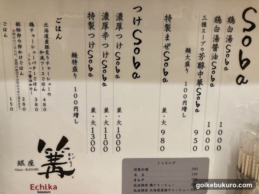 A close-up of a Japanese soba menu board featuring various noodle dishes with prices in yen, including special items and toppings list.
