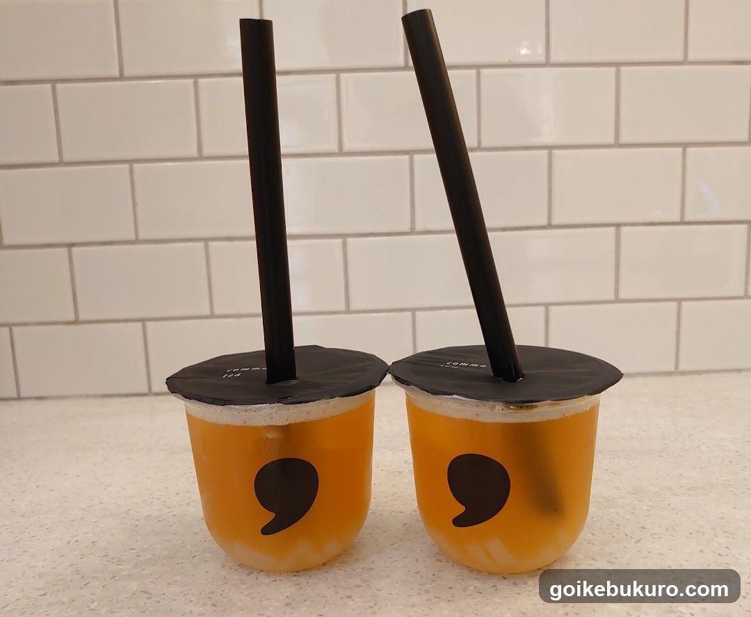 Two orange drinks with black straws