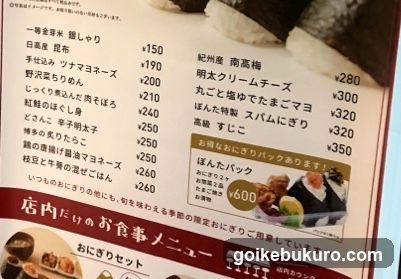 A close-up of a printed menu board listing various food items with prices in yen, including rice dishes, soups, and side dishes.