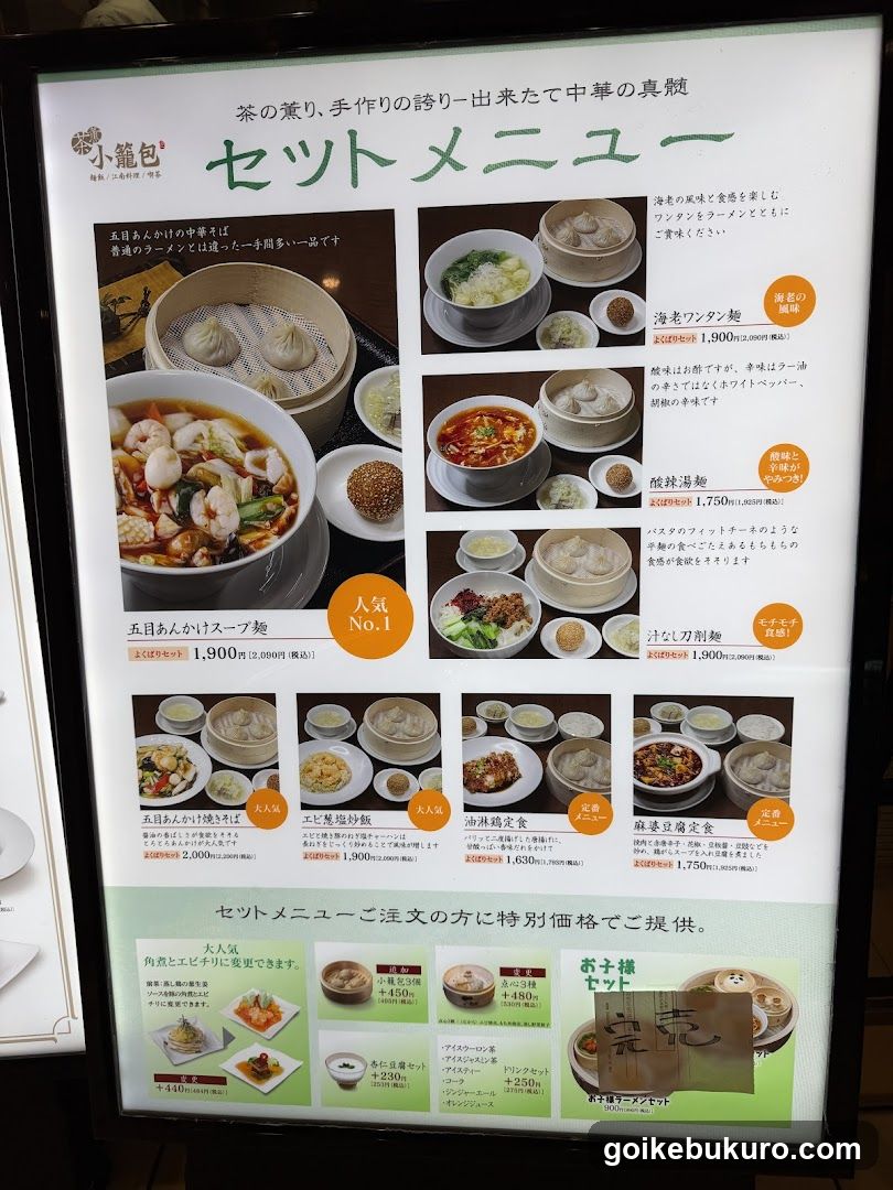 A menu board displaying various noodle dishes and soups with prices in yen, including items like Five-Ingredient Soup Noodles, Seafood Wonton Noodles, and Spicy Tofu Soup.