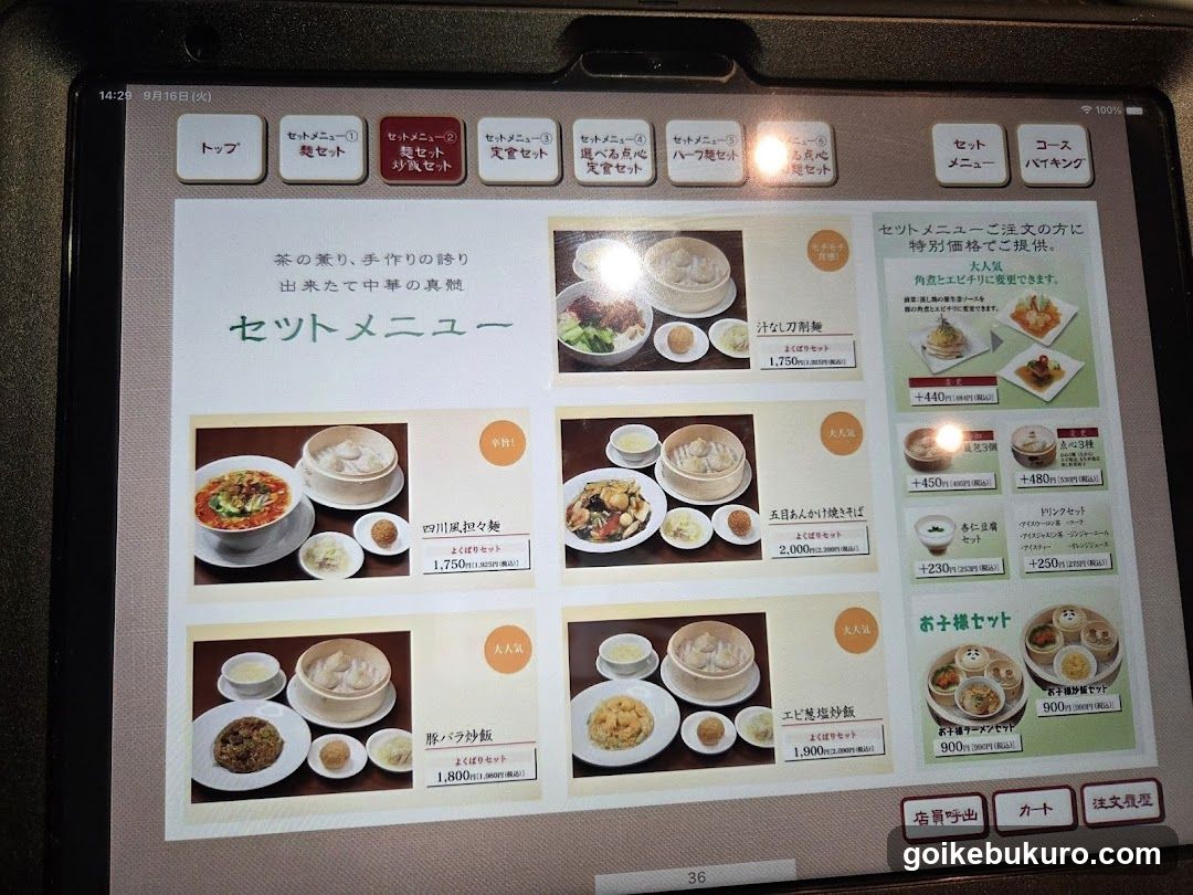 A close-up of a tablet screen displaying a Japanese restaurant's set menu. The screen shows various dishes with prices in yen, including Sichuan-style noodles, pork cutlet rice, and other options. The interface includes navigation buttons at the top and bottom.